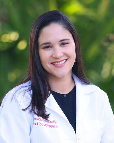 A woman in white lab coat standing outside.